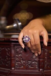 Crop anonymous female demonstrating creative flower shaped ring with shiny gemstones and brilliants while leaning on vintage gramophone